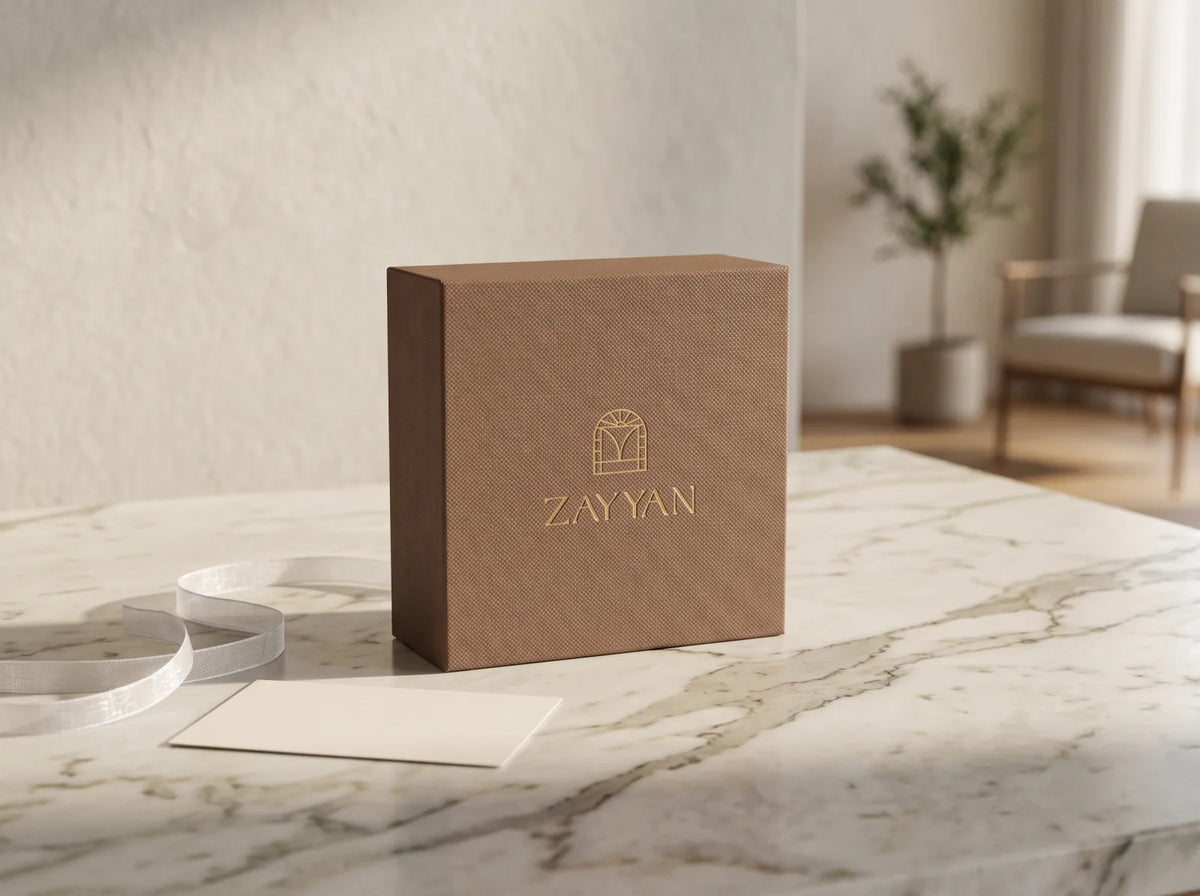 Coffret cadeau marocain Zayyan fermé sur une table en marbre, ruban d'organza et carte crème à côté