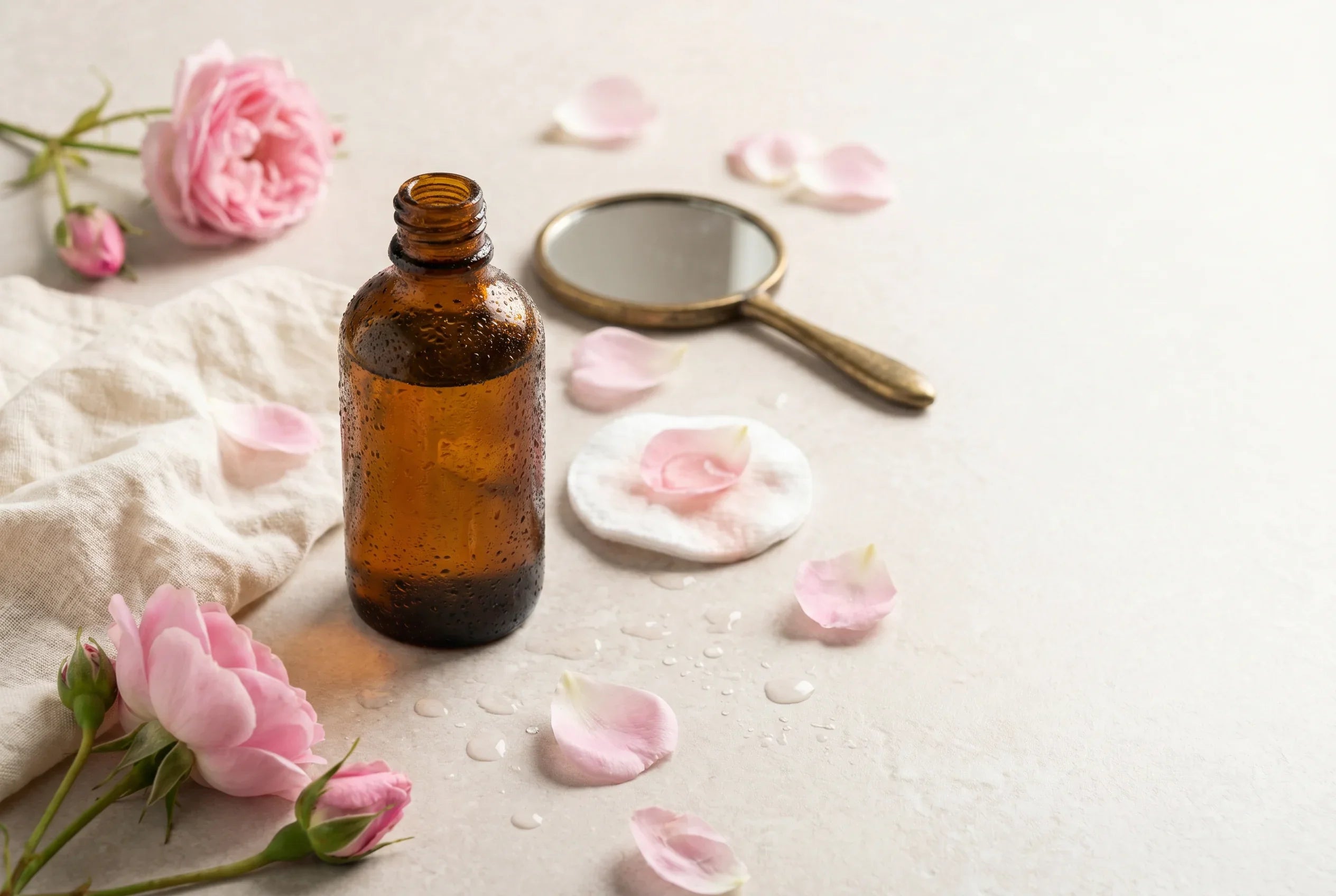 fiole d'eau de rose de damas entourée de pétales de rose
