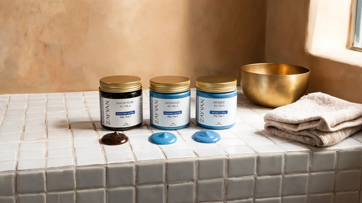 Les trois produits du pack Nila bleu Zayyan alignés sur un banc en zellige blanc, bol de laiton et serviette en lin