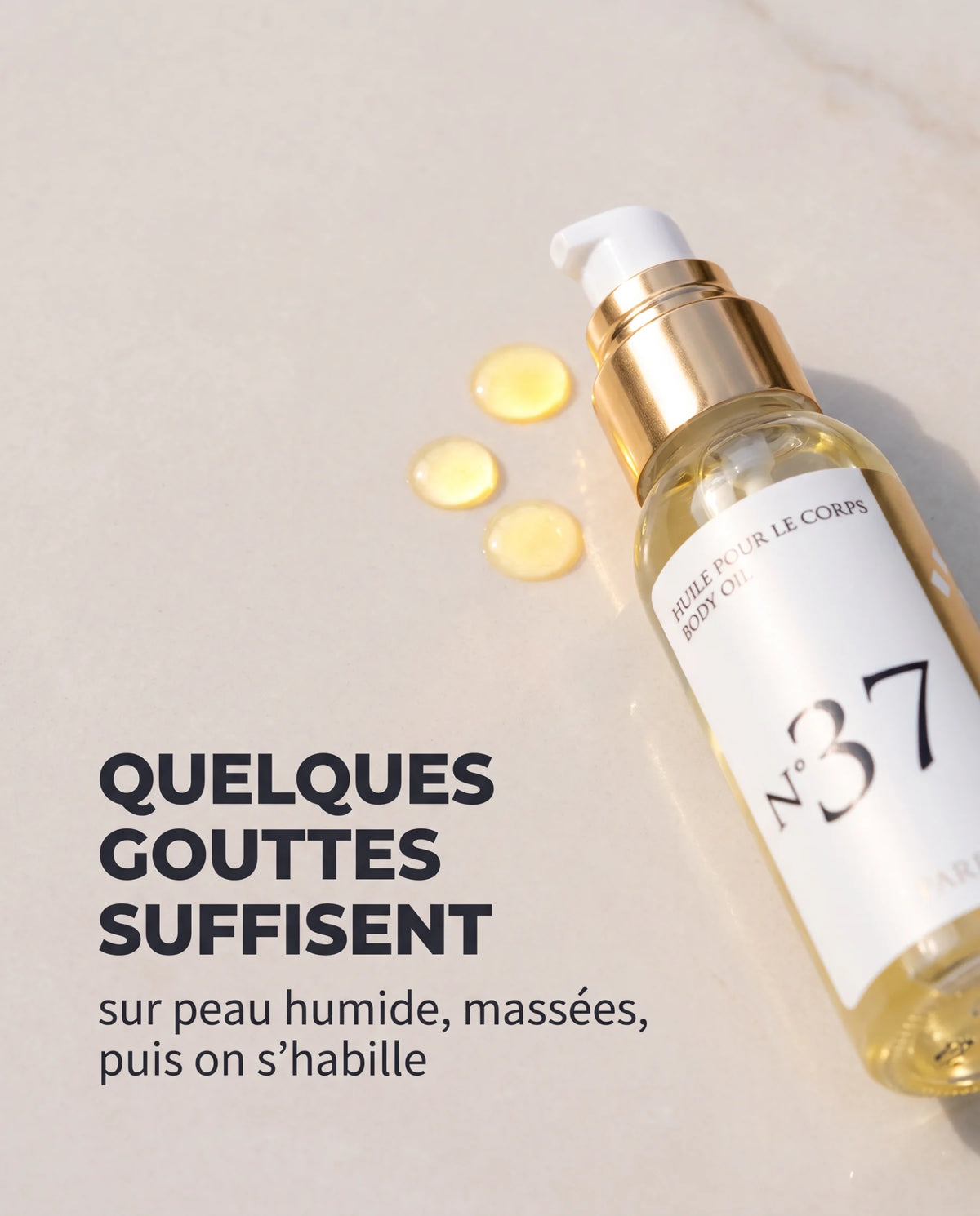 Trois gouttes d'huile d'amande douce parfumée sur une pierre claire, à côté du flacon pompe