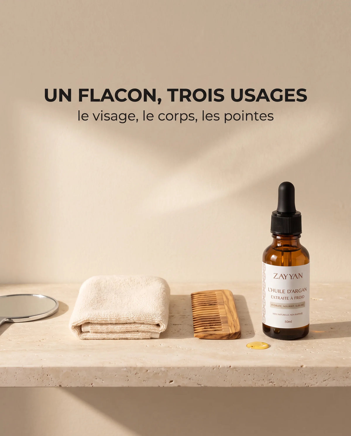 Huile d'argan Zayyan sur une étagère en travertin avec un miroir, une serviette et un peigne : un flacon, trois usages