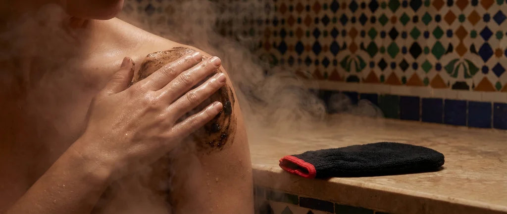 friction du savon noir sur la peau lors d'une session hammam marocain à l'aide d'un gant exfoliant dit kessa