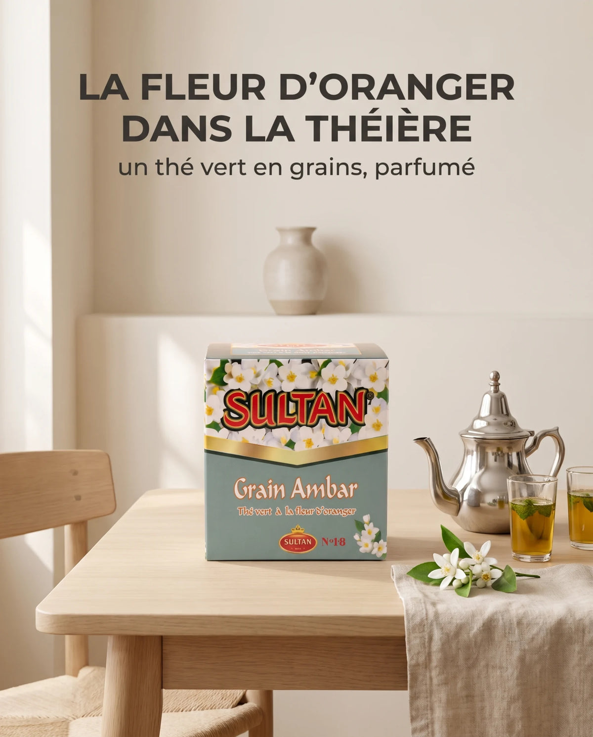 Boîte de thé Sultan Grain Ambar, théière en argent et fleurs d'oranger sur une table