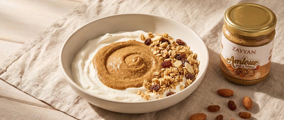 Bol de fromage blanc à l'amlou avec du muesli croustillant aux raisins et aux amandes, pot Zayyan à côté