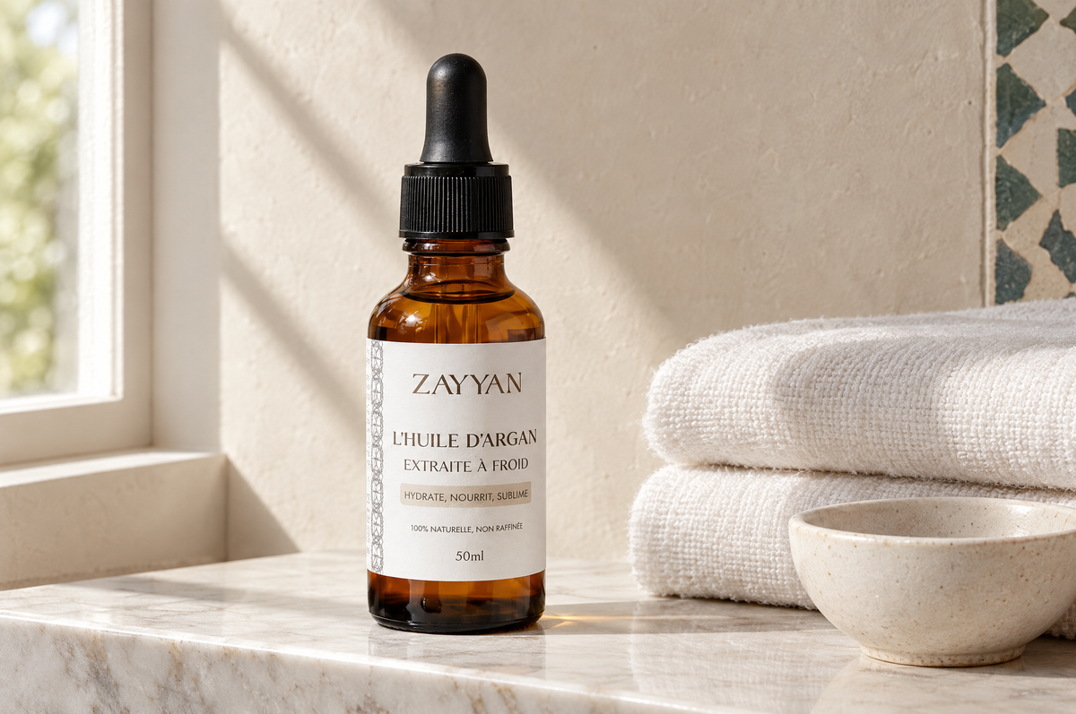 Huile d'argan bio Zayyan sur une tablette en marbre, à côté de linge de toilette plié