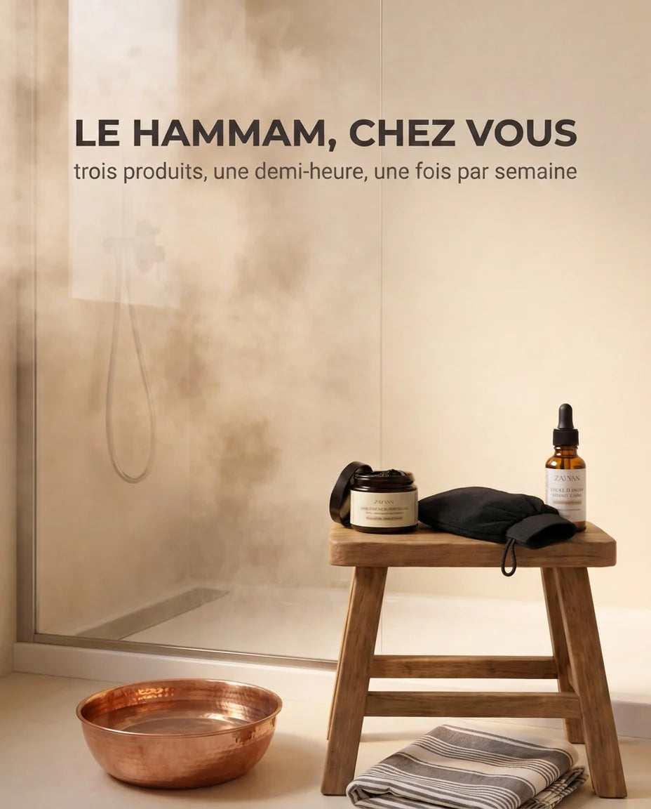 Savon noir, gant kessa et huile d'argan Zayyan sur un tabouret, dans une salle de bain pleine de vapeur
