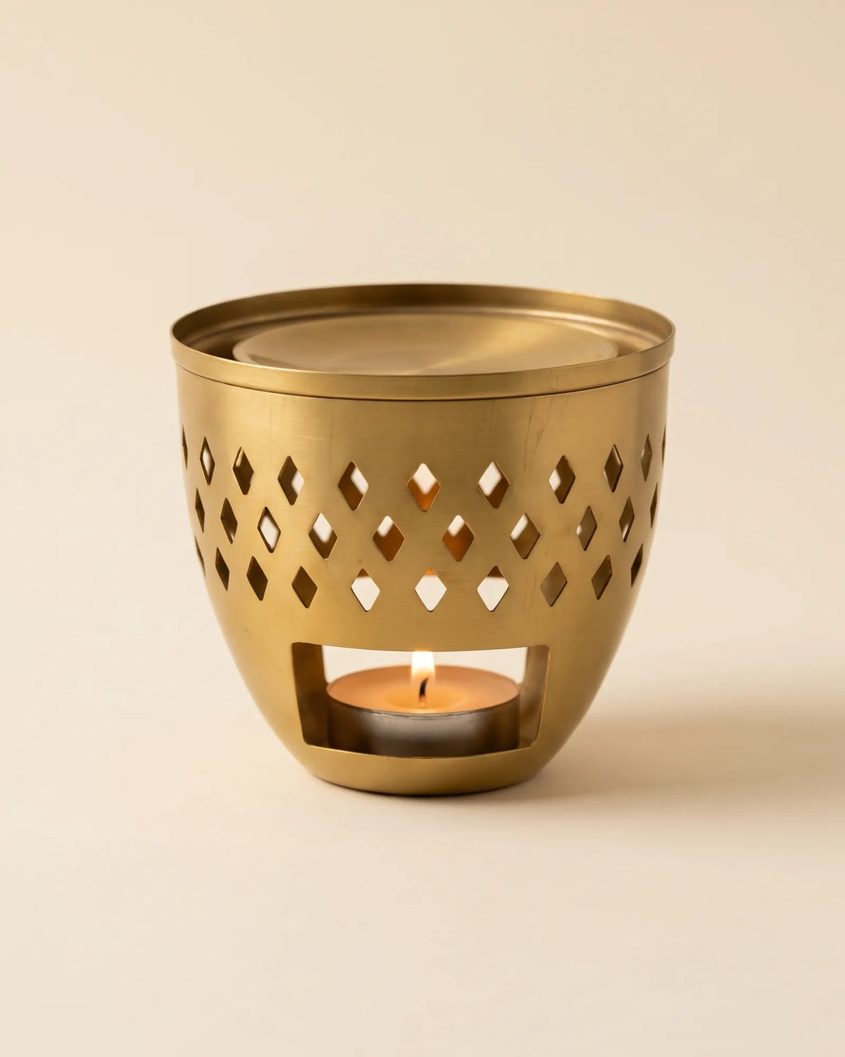Brûleur de parfum artisanal en laiton doré ajouré de losanges, bougie chauffe-plat allumée